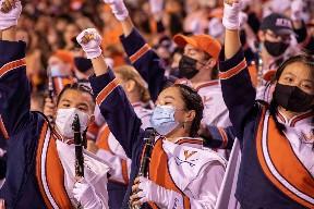 Masked members of the CMB cheer in the stands of Scott Stadium during a home football game. Until Sept. 16, members of the band were required to wear masks in the stands. (Photo: Tom Pajewski)